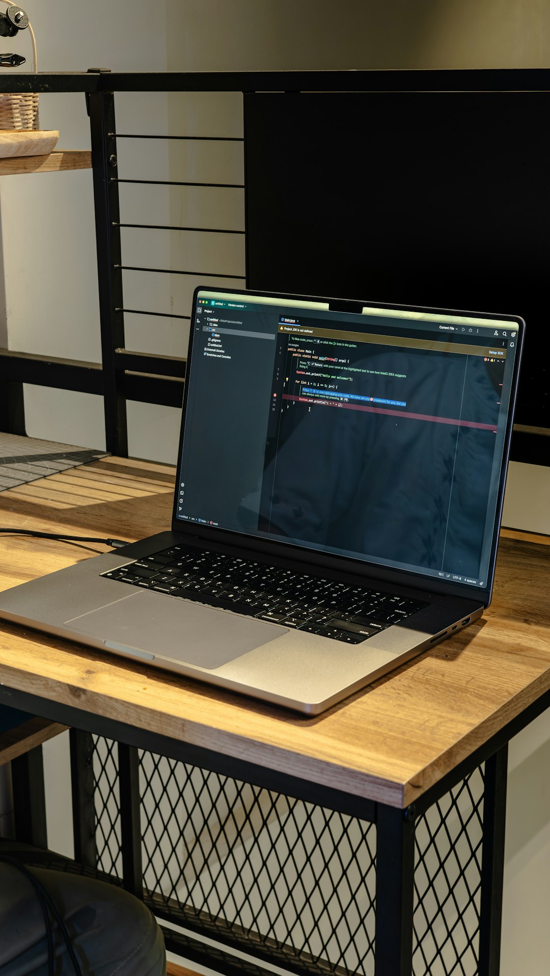 Warm-toned workspace featuring a laptop with programming code displayed on screen. A professional yet cozy setup suitable for illustrating remote work, software engineering, coding education, and modern tech careers.