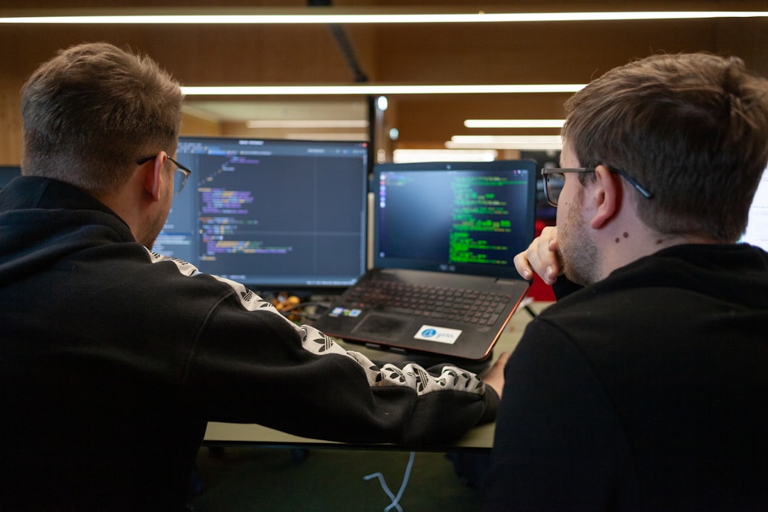 IT guys looking at a coding program on a laptop and monitor